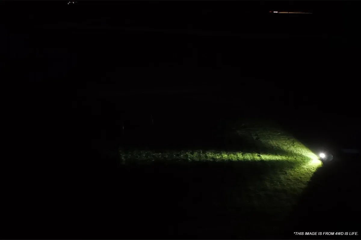 White auxiliary lighting revealing terrain to the side of an off road route