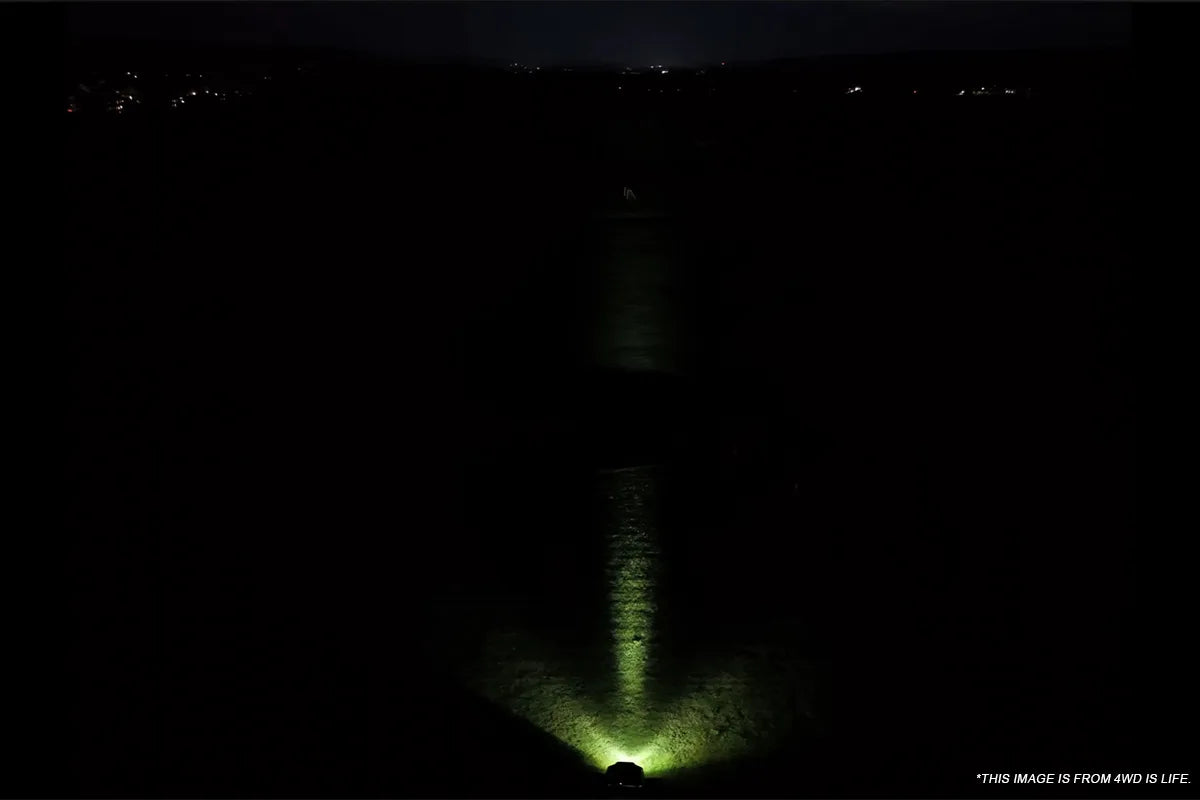 Focused white auxiliary lighting reaching into the distance on a dark trail
