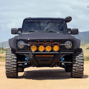 Four Suparee Helm 7 series round amber LED driving lights installed on the front bumper grille guard of a matte black Ford Bronco.